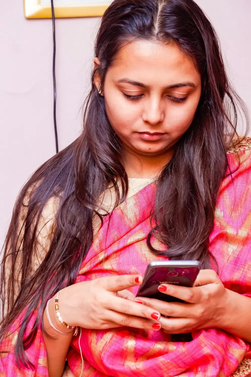 A woman in a pink sari using her phone