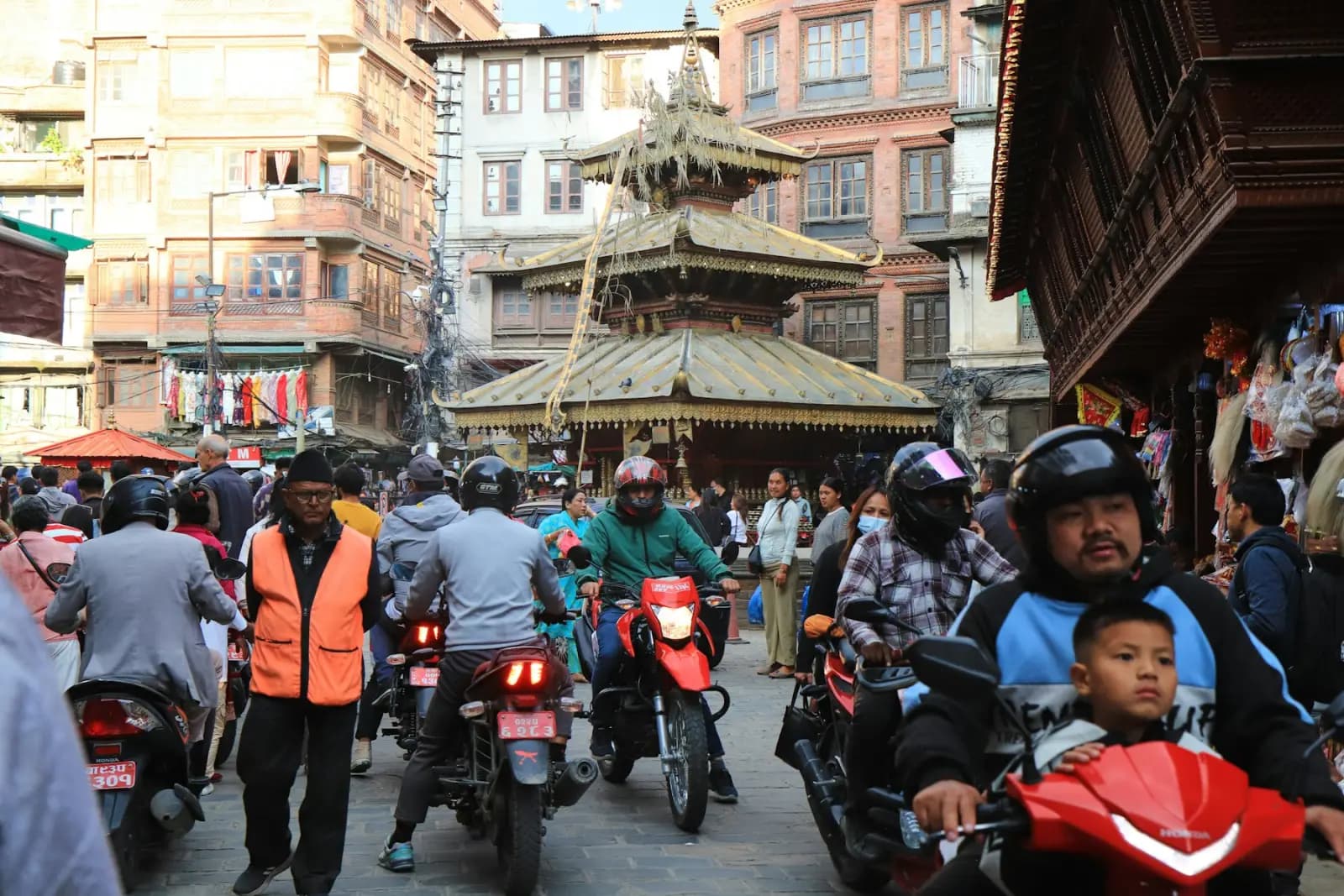 Motorbikes and scooters filling a street beside a temple in Kathmandu