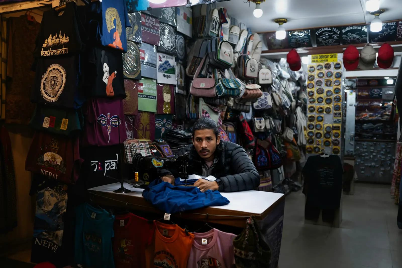 A shopkeeper at the counter of a busy clothing and souvenir shop in Kathmandu